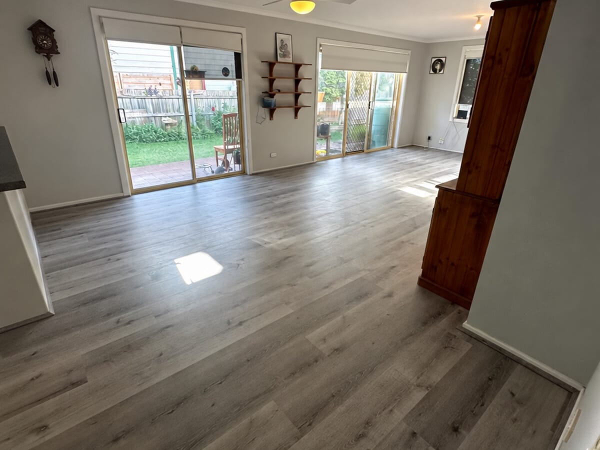 Dark Grey Oak 1005 hybrid planks running the length of an open living and dining room, with sliding doors to the back garden at either end.