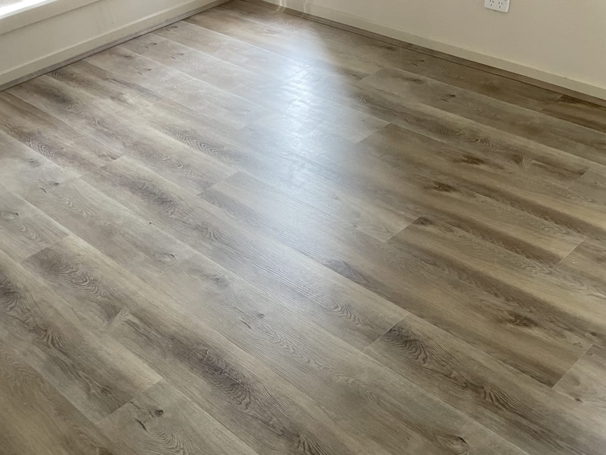 Coastal Oak 1009 planks in an empty room, low sun picking out the grain along the plank run.
