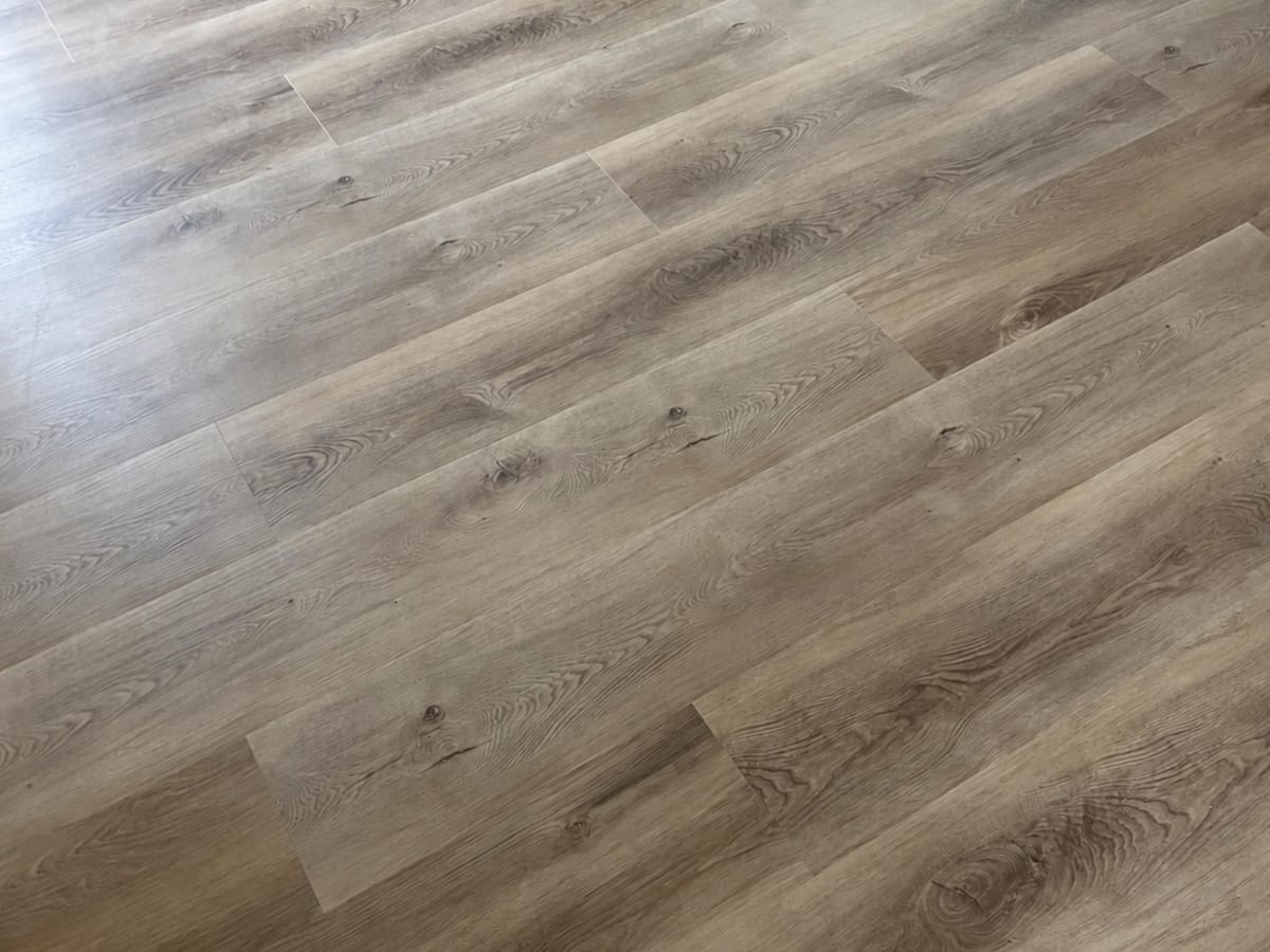 Close view of Coastal Oak 1009 planks meeting the skirting, showing the weathered greige grain and bevelled plank edges.