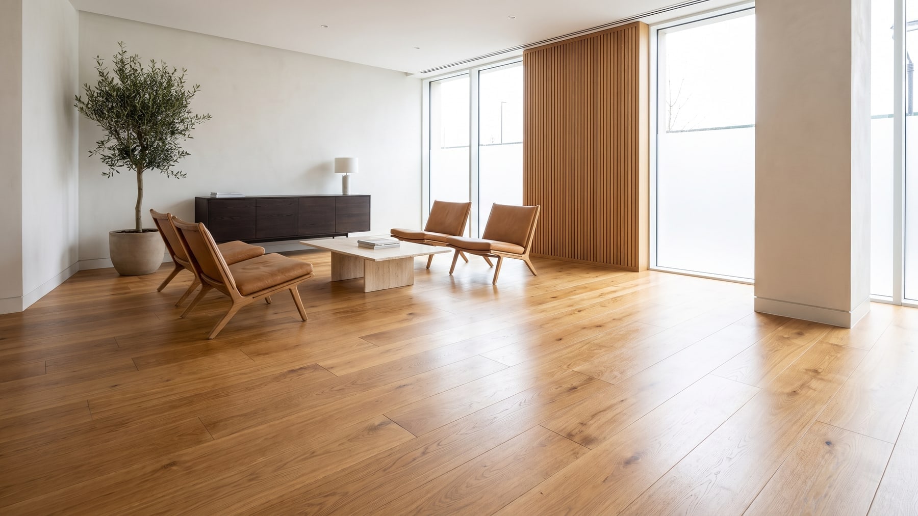 An open-plan commercial lobby with continuous wide-plank timber-look flooring, lounge seating and full-height glazing
